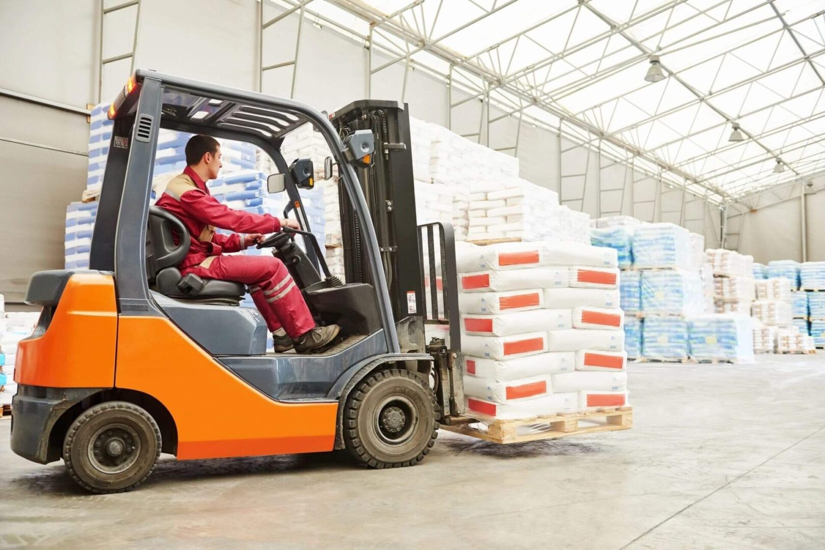 A man in red and white suit driving a forklift.