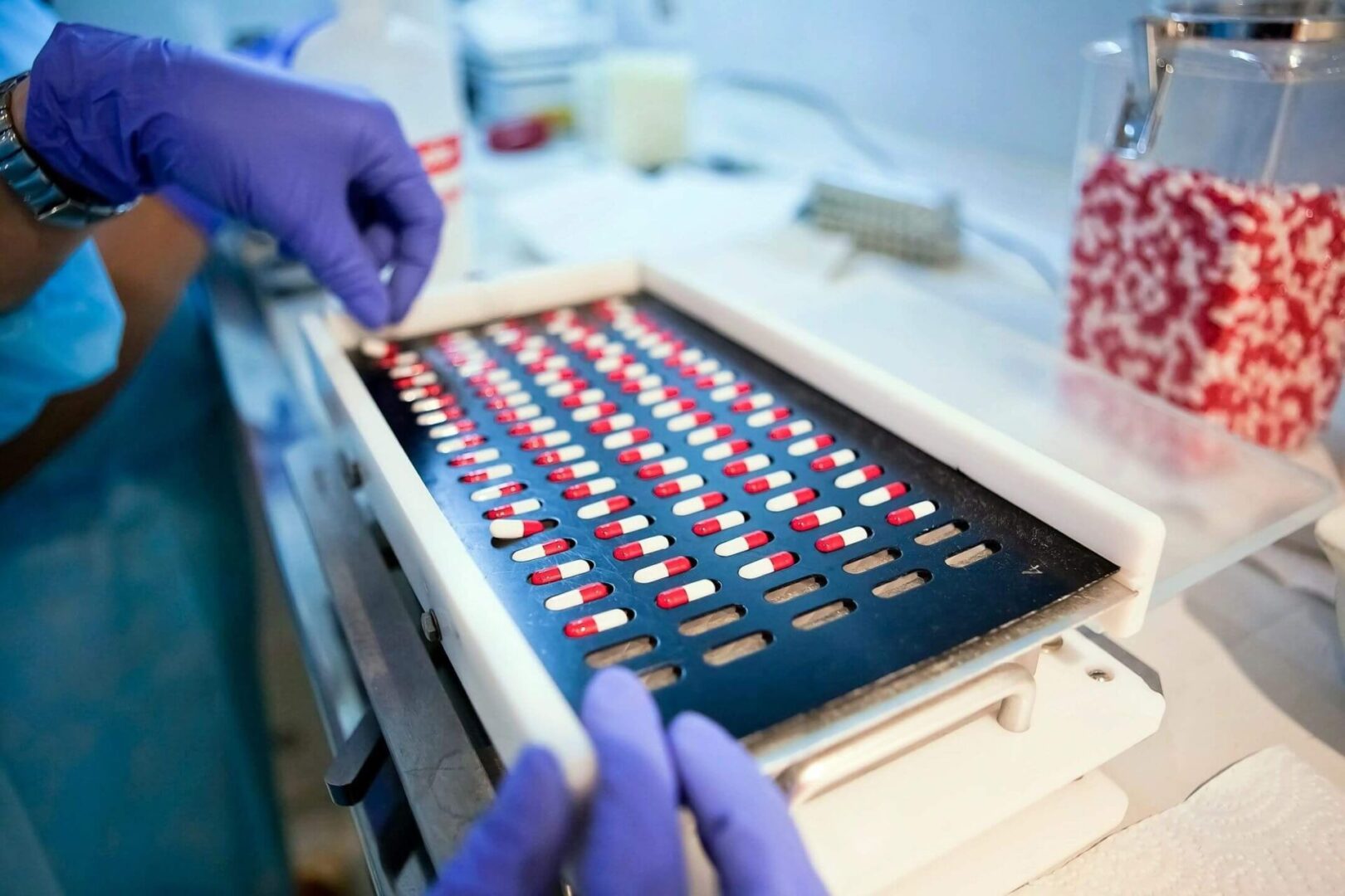 A person in blue gloves is working on a box of pills.